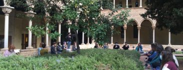 Persones assegudes mediten al voltant del pati del monestir ple de plantes